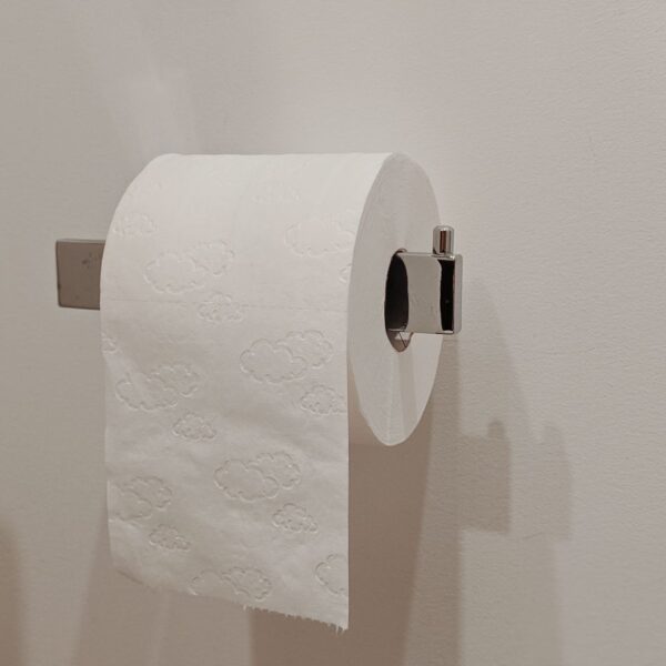 Toilet paper roll on a modern holder in a minimalist bathroom setting.